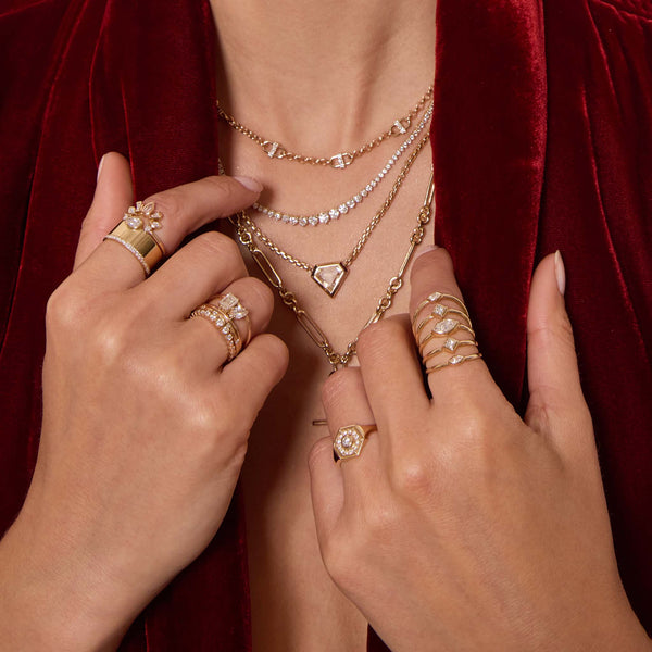 Zoe Chicco 14K Gold Close-up of hands wearing multiple gold and diamond rings and necklaces against a red velvet background