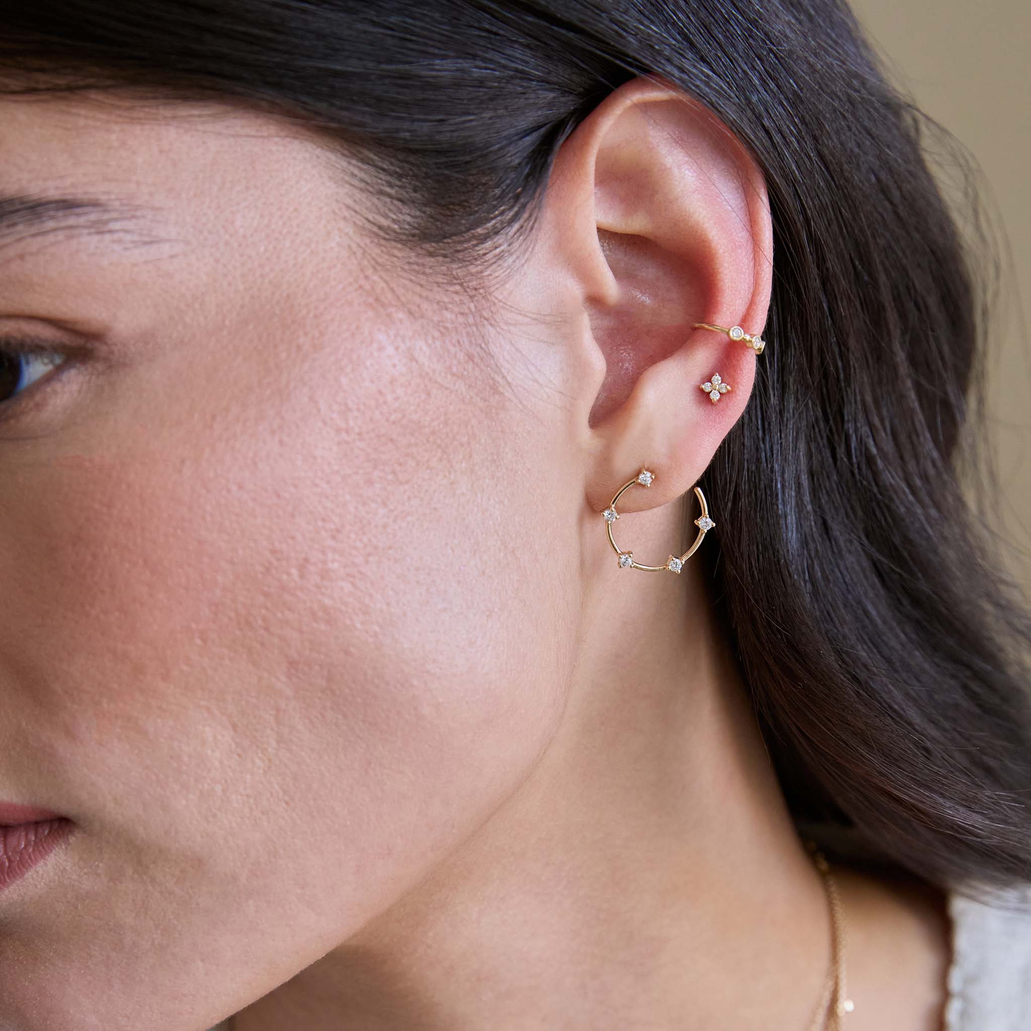 Close-up of a woman wearing Zoe Chicco 14k gold prong diamond open circle stud earring with a prong diamond quad stud and ear cuff