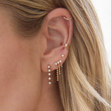 woman's ear wearing a Zoë Chicco 14k Gold Prong Diamond Dash Tennis Drop Earring layered with a 14k Prong Diamond  & Bead Chain Waterfall Earring, Prong Diamond Stud, and wearing a 14k Nested Prong Diamond Double Wire Ear Cuff