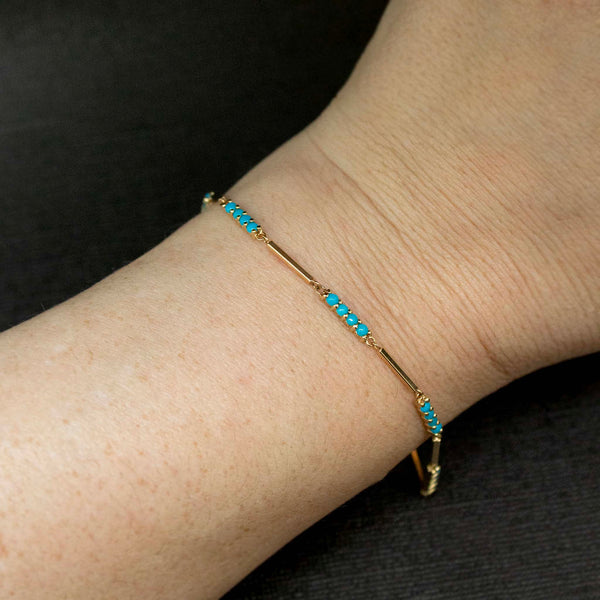 close up of a woman's wrist against a black background wearing a Zoë Chicco 14k Gold Mixed Gold & Turquoise Bar Bracelet
