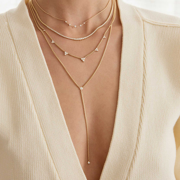 Zoe Chicco 14K Layered gold necklaces on a person wearing a beige top.