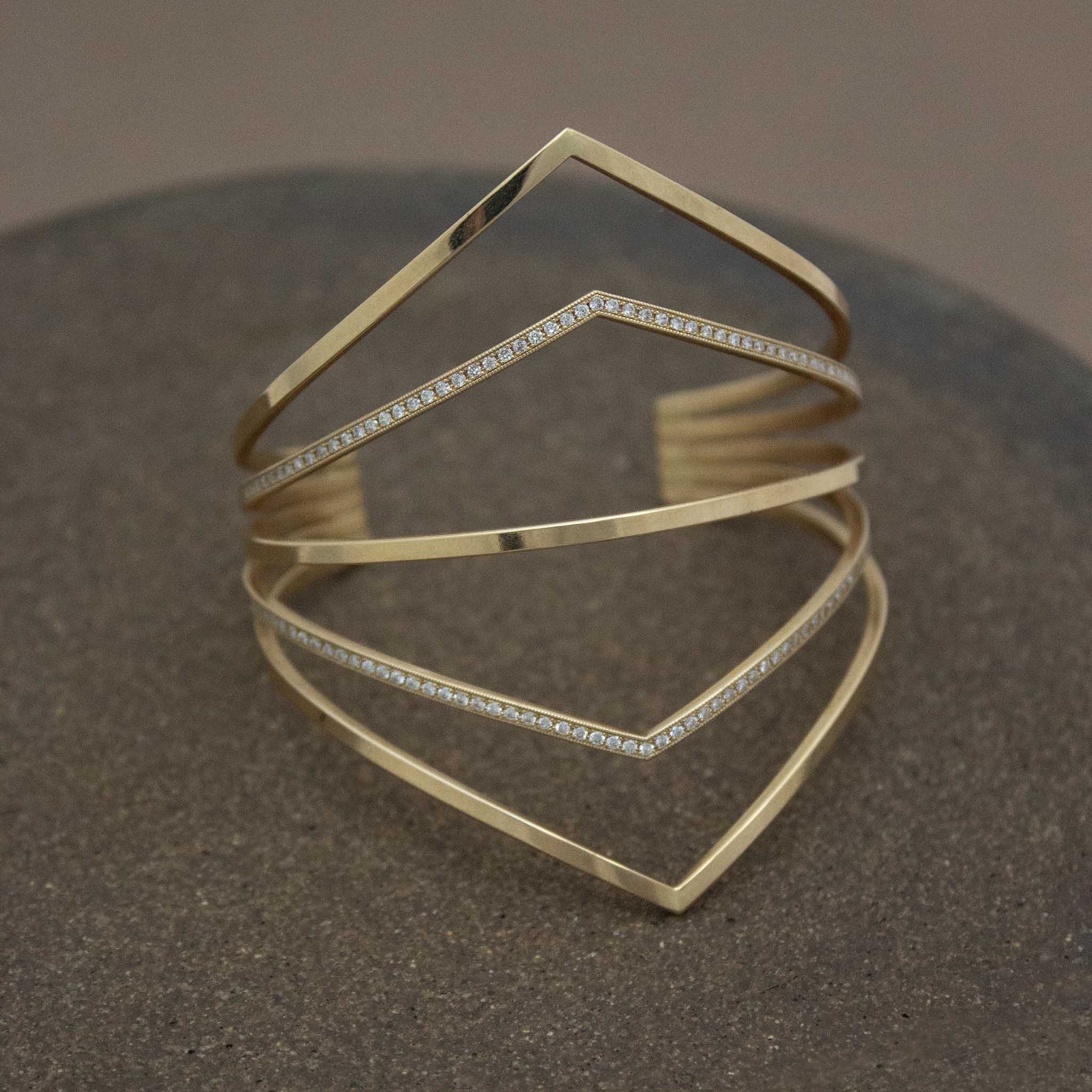 14k 5 Pointed Bar Cuff with Pavé Diamonds laying on a brown background