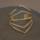 14k 5 Pointed Bar Cuff with Pavé Diamonds laying on a brown background