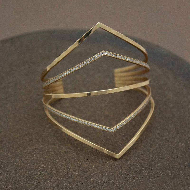 14k 5 Pointed Bar Cuff with Pavé Diamonds laying on a brown background
