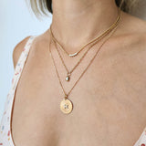 woman wearing a Zoë Chicco 14k Gold 5 Diamond Bezel Bar Extra Small Curb Chain Necklace layered with two necklaces