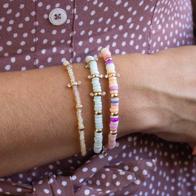 woman's wrist waring a Zoë Chicco 14k Gold & Mixed Light Blue Opal Rondelle Bead Bracelet with 6 Prong Diamonds layered with a 14k Gold & Mixed Pink Opal Rondelle Bead Bracelet with 2 Prong Diamonds and a 14k Gold & Fire Opal Rondelle Bead Bracelet with 2 Prong Diamonds