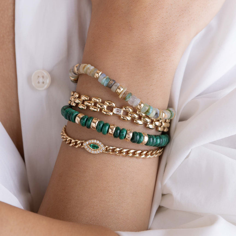 close up of a woman's wrist wearing a Zoë Chicco 14k Gold & Malachite Rondelle Bead Bracelet stacked with a 14k Gold & Mixed Neutral Gemstone Rondelle Bead Bracelet, 14k Emerald Cut Diamond Bezel Medium Panther Chain Bracelet, and a Marquise Emerald Diamond Halo Curb Chain Bracelet