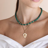 woman in a white top wearing a Zoë Chicco 14k Gold & Malachite Rondelle Bead Necklace with 3 Prong Diamonds layered with a Lion Head Diamond Shield Pendant Curb Chain Necklace