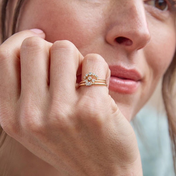 close up of a woman's hand wearing a Zoë Chicco 14k Gold 3 Graduated Prong Diamond Curve Ring stacked with a Marquise Diamond Ring and a 14k Graduated Prong Diamond Arch Ring on her pinky finger