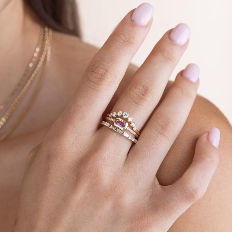 woman resting her hand on her shoulder wearing a Zoë Chicco 14k Gold Emerald Cut Pink Sapphire Bezel Pavé Diamond Band Ring stacked with a Horizontal Baguette Eternity Band Ring and a 14k Graduated Prong Diamond Arch Ring