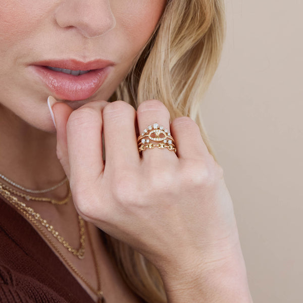 woman's hand resting on her chin wearing a Zoë Chicco 14k Gold Single Pavé Diamond Large Mariner Link Ring stacked with a 14k Graduated Prong Diamond Curved Bar Ring, 14k Double Mixed Prong Diamond Open Ring, and a 14k Gold Small Puffed Mariner Link Eternity Ring 