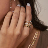 close up of woman's hand resting on her neck wearing a Zoë Chicco 14k Gold Marquise Diamond Thick Band Ring stacked with four other diamond rings on her index finger
