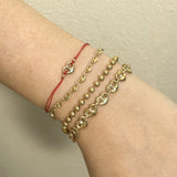 Gold bracelets on a wrist against a neutral background