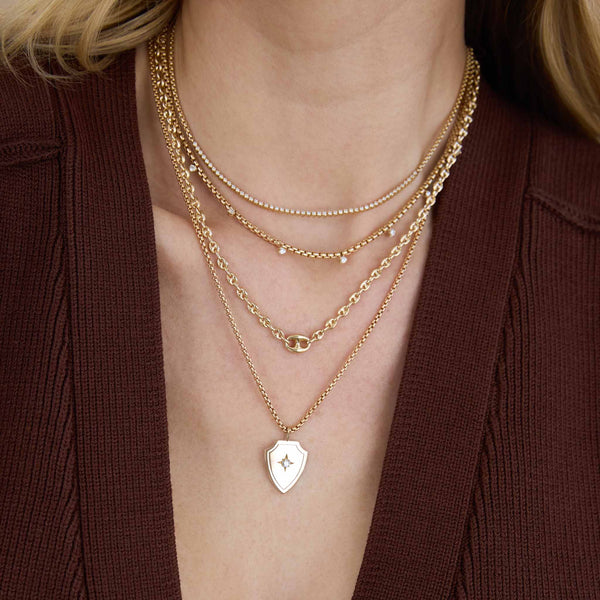 woman in a maroon sweater wearing a Zoë Chicco 14k Gold Single Large Mariner Link Small Mariner Chain Necklace layered with a Prong Diamond Tennis Necklace, 14k 9 Prong Diamond Medium Box Chain Necklace, and a 14k Diamond Shield Pendant Box Chain Necklace