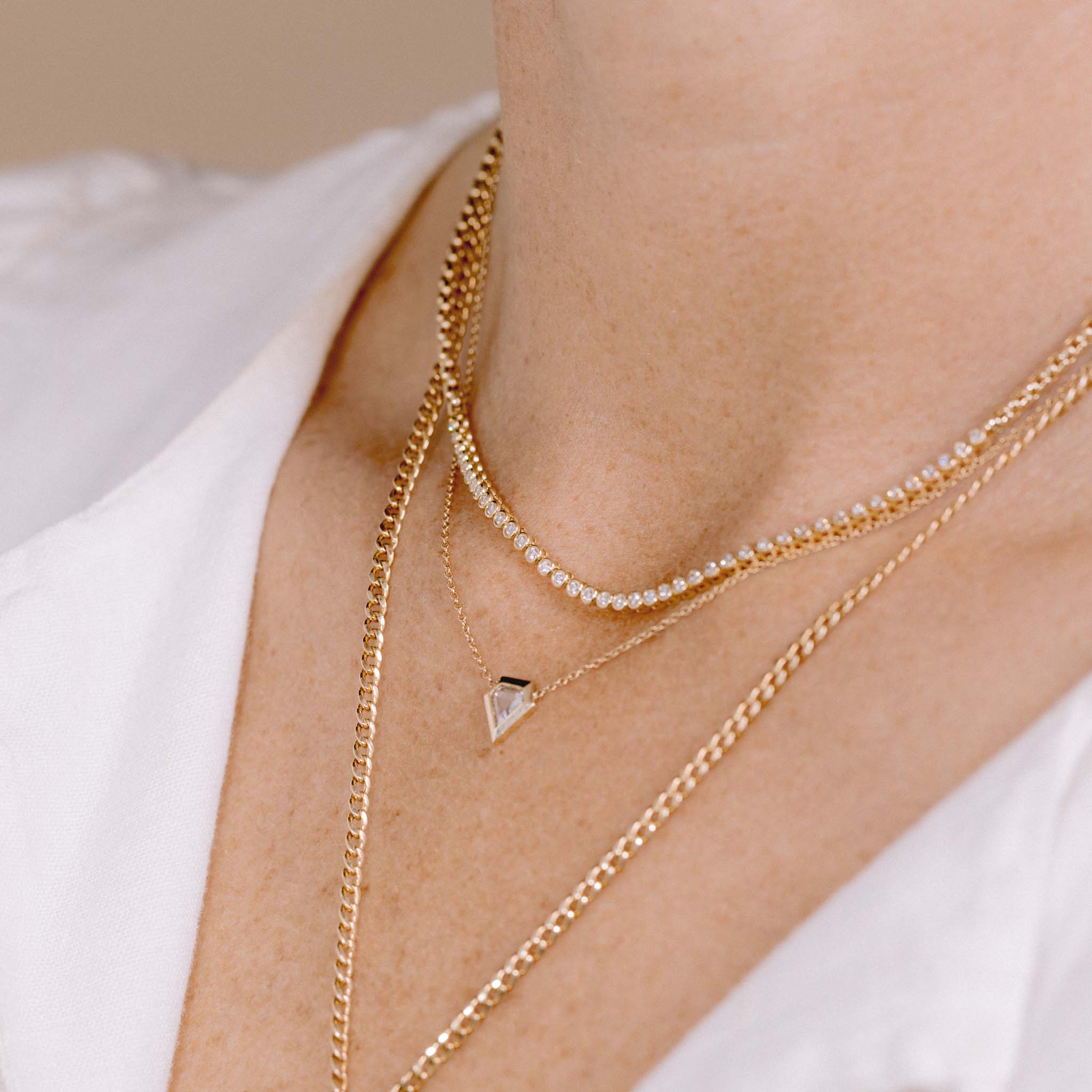 woman wearing a Zoë Chicco 14k Gold .28 ctw Shield Diamond Bezel Necklace layered with a 14k Small Diamond Bezel Tennis Segment Box Chain Necklace