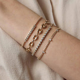 woman's wrist wearing a Zoë Chicco 14k Gold 2.5mm Diamond Bezel Tennis Bracelet stacked with a 14k 5 Vertical Baguette Diamond Station Small Curb Chain Bracelet, 14k Gold Large Puffed Mariner Chain Bracelet, and a 14k Vertical Emerald Cut Diamond Tennis Segment Box Chain Bracelet
