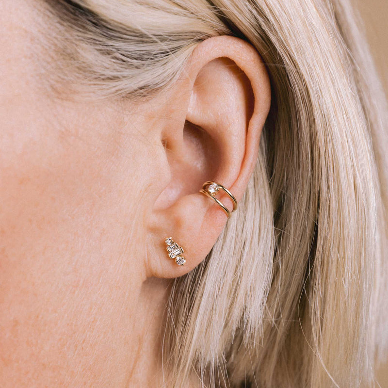 woman's ear wearing a Zoë Chicco 14k Gold Graduated Baguette & Prong Diamond Stacked Stud Earring and a 14k Nested Prong Diamond Double Wire Ear Cuff