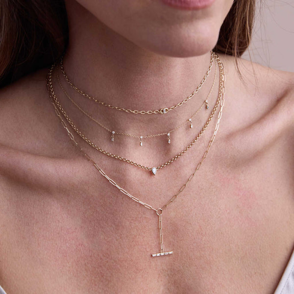 close up of a woman wearing a Zoë Chicco 14k Gold Channel Set Baguette Diamond Bar Paperclip Chain Lariat Necklace layered with a 14k Baguette Diamond Open Link Square Oval Chain Necklace and a Pear Diamond Bezel Rolo Chain Necklace