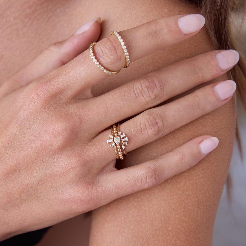 woman's hand resting on her shoulder wearing a Zoë Chicco 14k Gold Tapered Baguette Diamond 3 Stone Fan Ring stacked with a 14k Tapered Baguette Diamond 5 Stone Fan Ring and 14k Horizontal Pear Diamond Beaded Ring on her ring finger