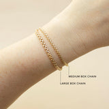 An image of a woman's wrist comparing Zoë Chicco 14k Gold Large Box Chain Bracelet with a Medium Box Chain Bracelet