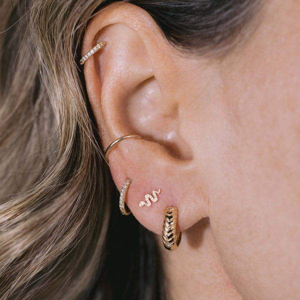 Zoe Chicco's 14k Gold Braided Hinge Huggie Hoops, Ity Bitty Snake Stud and Pave Hinged Huggie are stacked in the first three piercings