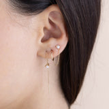 brunette woman's ear wearing a Zoë Chicco 14k Gold Pearl Stud & Huggie Hoop Linked Double Earring in her second and third piercing and layered with a 14k Pearl Loop Threader Earring