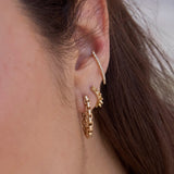 close up of a woman's ear wearing a Zoë Chicco 14k Gold Large Box Chain Huggie Earring layered with a 14k Gold Spiked Hinge Huggie Hoop in her second piercing and a 14k Pavé Diamond Thick Wire Bar Ear Cuff
