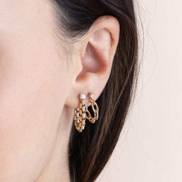 close up of a woman's ear wearing a Zoë Chicco 14k Gold Prong Diamond Large Box Chain Huggie Earring layered with a Prong Diamond Medium Square Oval Link Huggie Hoop in her second piercing