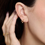 Close-up of a person wearing Zoe Chicco 14k gold earrings and rings with a blurred background