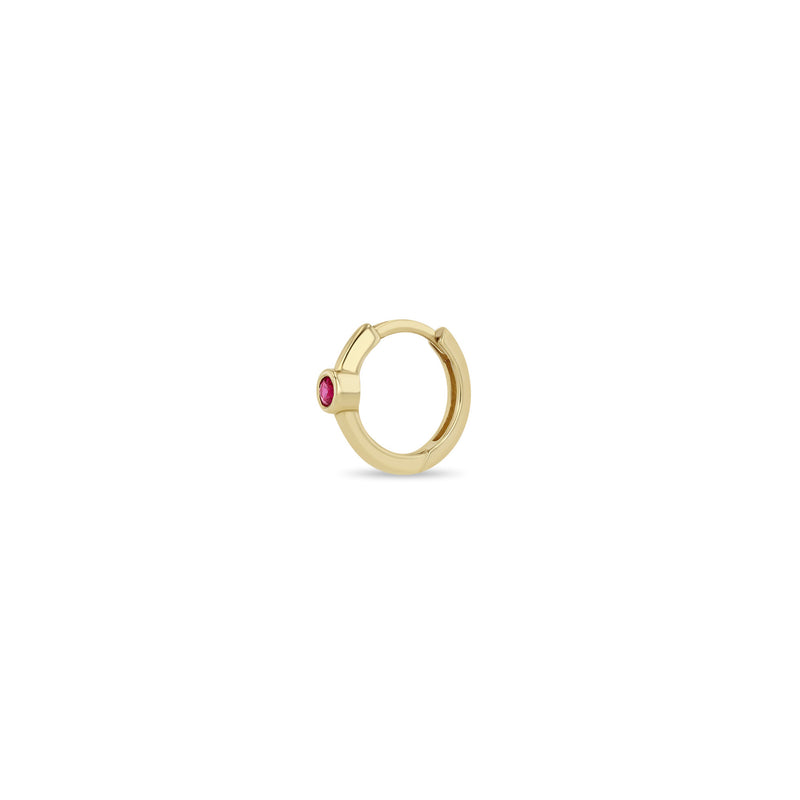 Angled view of a Zoë Chicco 14k Gold Single Ruby Bezel Small Hinge Huggie Hoop Earring