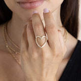 close up of a woman's hand raised up wearing a Zoë Chicco 14k Gold Diamond Bezel Heart Ring on her middle finger