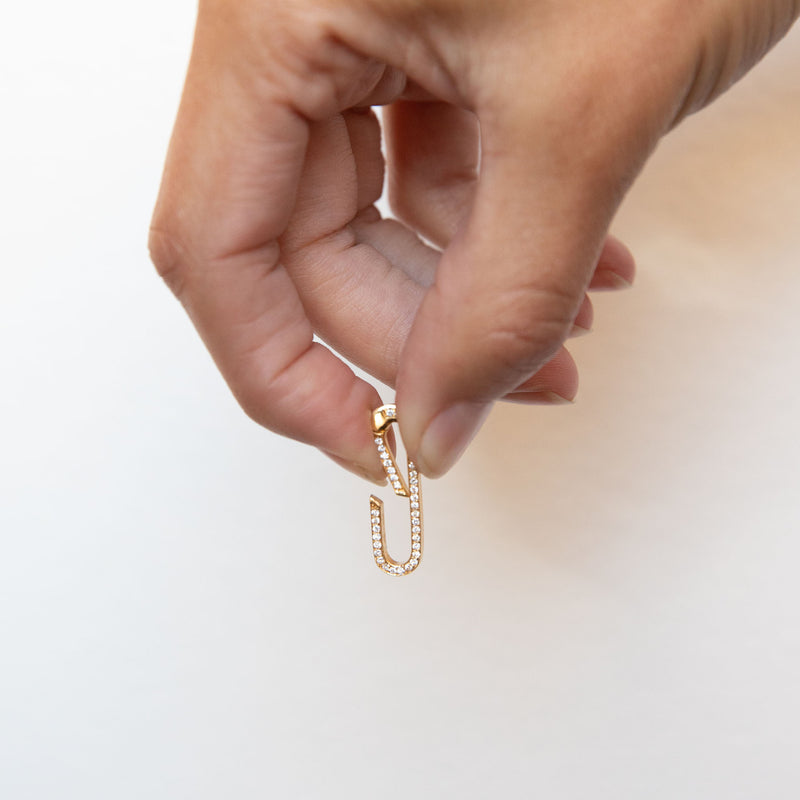 a hand holding a Zoë Chicco 14k Gold Large Pavé Diamond Oval Push Lock Enhancer demonstrating how to open the enhancer