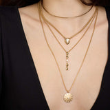 Close up of a woman's neck wearing layers of chain and diamond Zoe Chicco 14k gold necklaces on a dark background