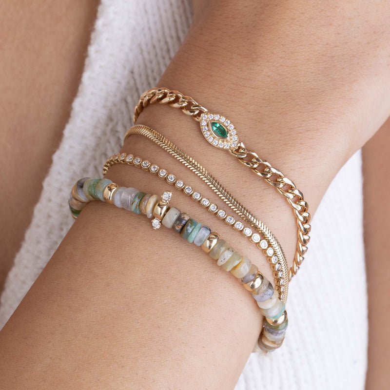 woman's wrist wearing a Zoë Chicco 14k Gold & Mixed Neutral Gemstone Rondelle Bead Bracelet with 2 Prong Diamonds stacked with a Diamond Bezel Tennis Bracelet, a Small Snake Chain Bracelet, and a Marquise Emerald Diamond Halo Curb Chain Bracelet