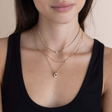 woman in a black tank top wearing a Zoë Chicco 14k Gold Large Floating Diamond Small Snake Chain Necklace layered with a 14k Mixed XS Curb & Small Paperclip Chain Necklace and a 14k Double Linked Pavé Diamond Knot Necklace
