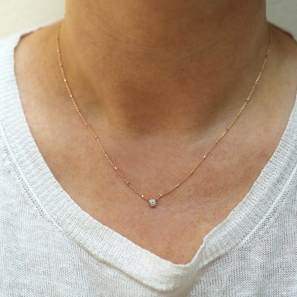 A woman in white knit top is wearing Zoe Chicco's 14k Floating Diamond Mixed Gold Satellite Chain Necklace.