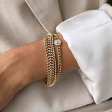 a woman in a beige blazer wearing a Zoë Chicco 14k Gold Double Wide Curb Chain Bracelet stacked with two other bracelets