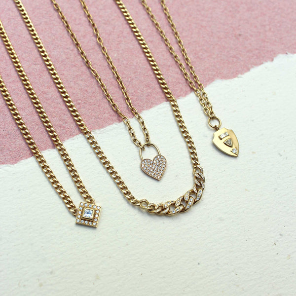 a Zoë Chicco 14k Gold Pavé Diamond Heart Padlock Square Oval Link Necklace laying flat with three other necklaces against a pink and white background