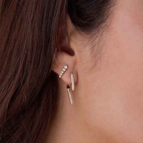 a brunette woman's ear wearing a Single Zoë Chicco 14k Gold Pavé Diamond Talon Earring layered with a Diamond Ice Pick Stud