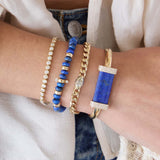 Close-up of a wrist wearing multiple Zoe Chicco bracelets with blue and gold accents featuring 14k gold large Lapis & Pavé Diamond Bar Half Round Cuff