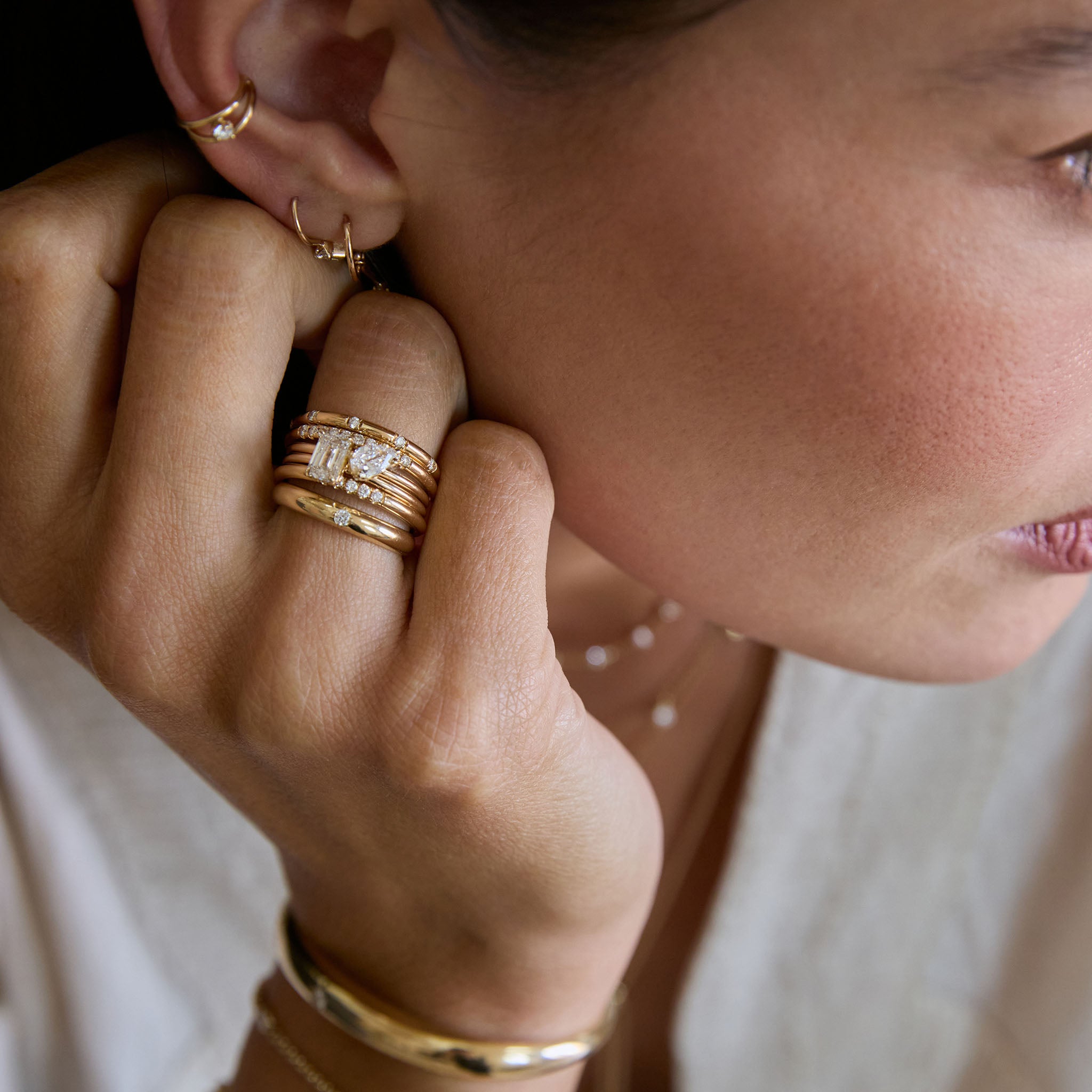 Close-up of a hand wearing Zoe Chicco 14k gold emerald cut and pear-shaped diamond rings