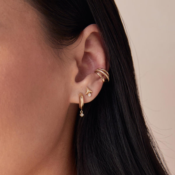a close up of a woman's ear wearing a Zoë Chicco 14k Gold Diamond & Triangle Pyramid Stud Earring in her second piercing