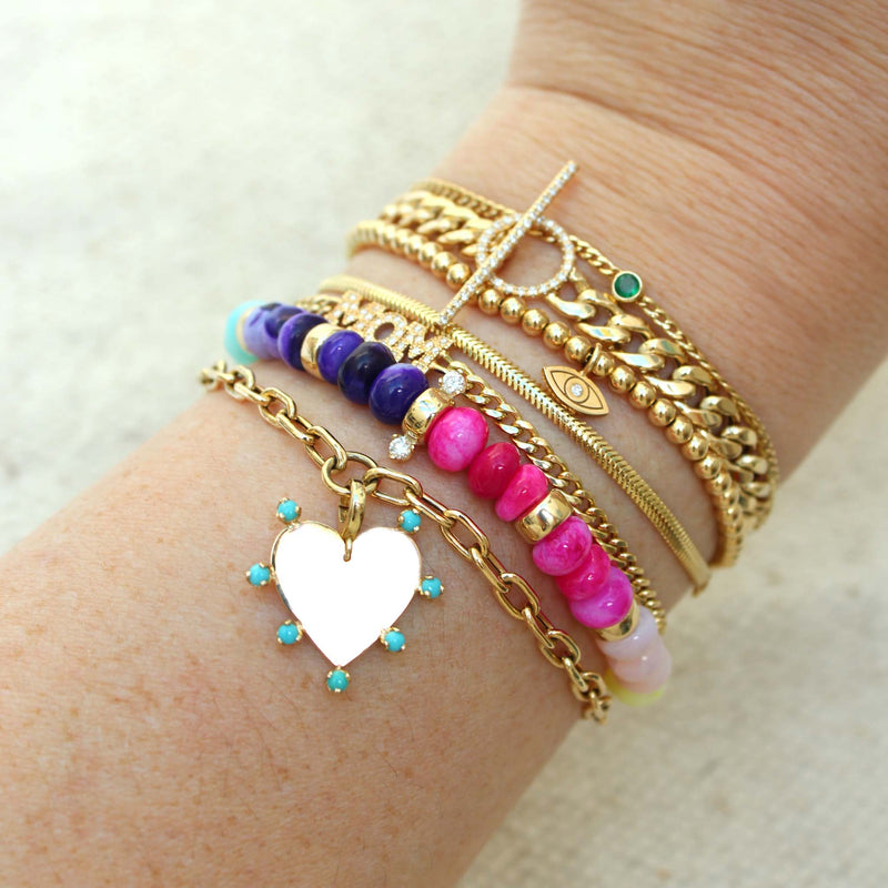 a woman's wrist wearing a Zoë Chicco 14k Gold Small Snake Chain Bracelet stacked with several other bracelets