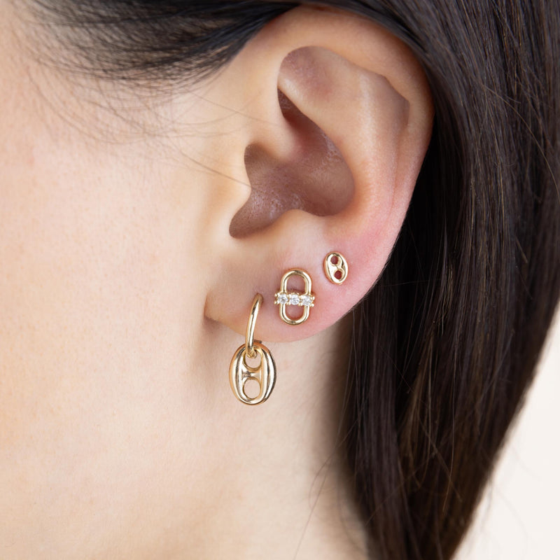 close up of a woman's ear wearing a Zoë Chicco 14k Gold Dangling Large Mariner Link Medium Hinge Huggie Hoop layered with a 14k 3 Prong Diamond Open Link Stud and a Small Mariner Link Stud