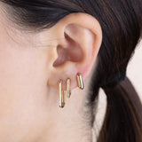 a woman with dark hair is wearing Zoe Chicco's 14k 3 Diamond Thick Large Oval Hinge Hoops, 14k Pavé Diamond Thick Medium Oval Hinge Hoops and 14k Gold Thick Small Oval Hinge Huggie Hoops