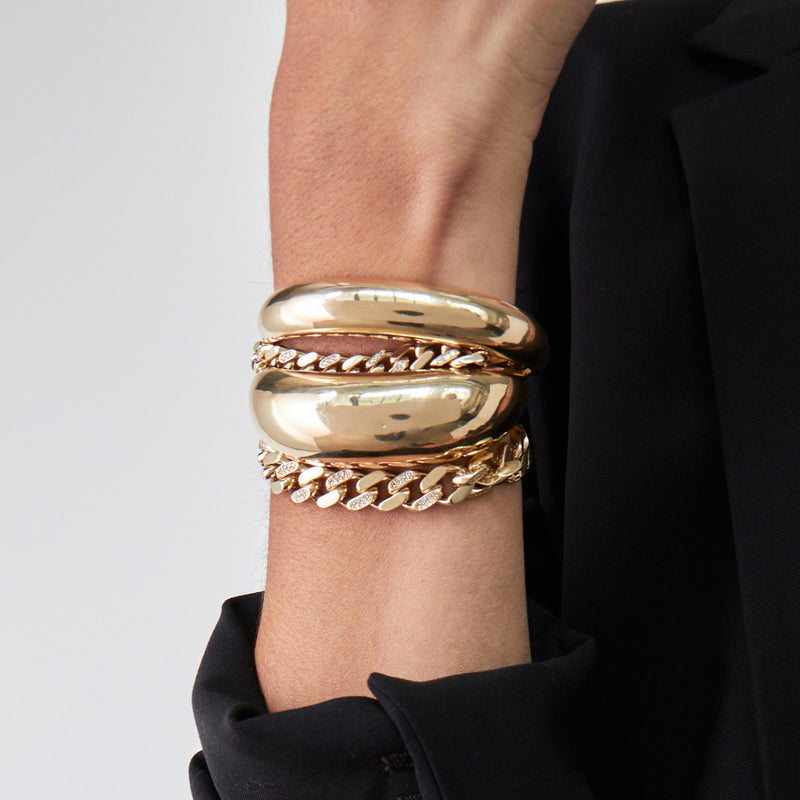 woman wearing a Zoë Chicco 14k Gold & Alternating Pavé Diamond XL Curb Chain Bracelet stacked with two aura cuff bracelets on her wrist