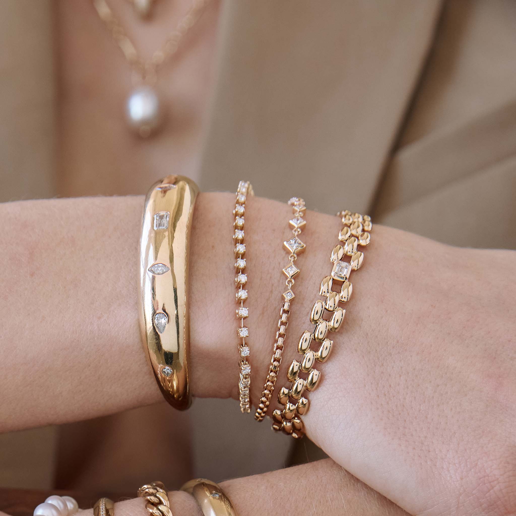 close up of a woman's wrist wearing a Zoë Chicco 14k Gold Prong Diamond Dash Tennis Bracelet stacked with a 14k Mixed Cut Diamonds Medium Aura Cuff, 14k Linked Graduated Princess Diamond Bezel Box Chain Bracelet, and a 14k Emerald Cut Diamond Medium Panther Chain Bracelet