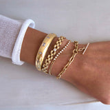 woman's arm against a white background wearing a Zoë Chicco 14k Gold Emerald Cut Diamond Medium Panther Chain Bracelet stacked with a 14k Mixed Cut Diamonds Medium Aura Cuff, 14k Diamond Tennis Segment Small Curb Chain Bracelet, and a 14k Extra Large Square Oval Chain Pavé Diamond Toggle Bracelet