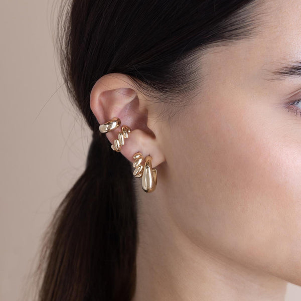 brunette woman wearing a Zoë Chicco 14k Gold San Marco Huggie Hoop Earring in her second piercing layered with a Medium Aura Hoop,  Chubby Ear Cuff and a San Marco Chain Ear Cuff