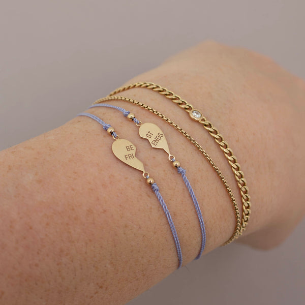 a woman wears 14k Midi Bitty Best Friends Heart Cord Bracelet Set and a small curb bracelet with floating diamond